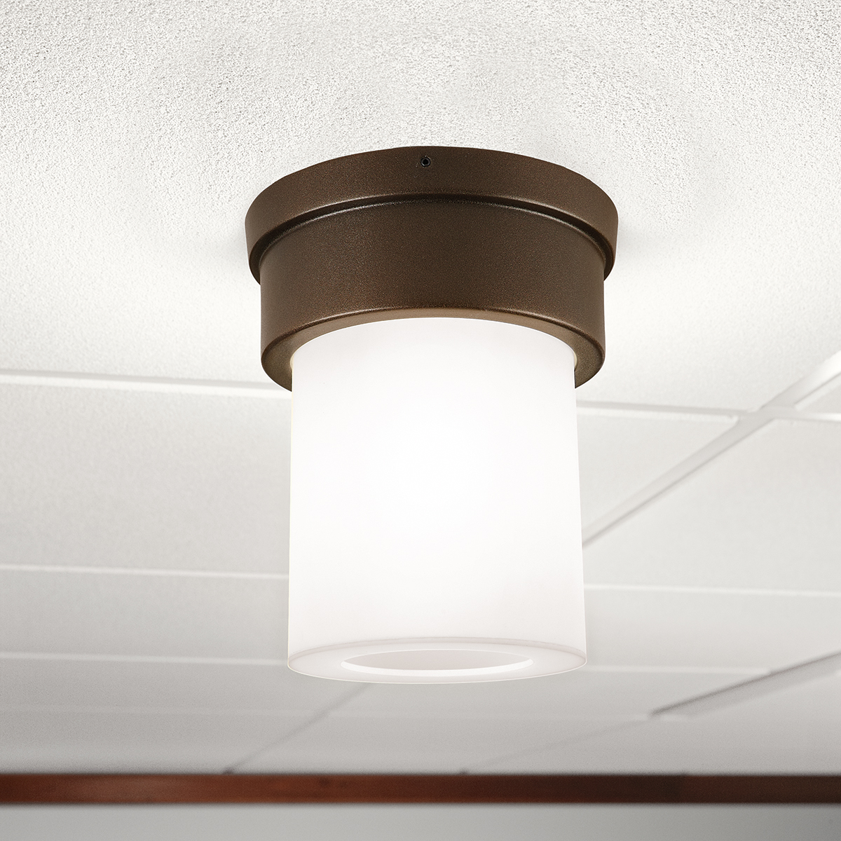 A small, luminous ceiling-mounted cylinder fixture with a solid base
