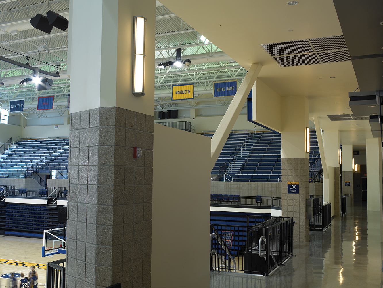 Avatar wall sconces with minimal accent provide modern lighting design for a college basketball gym.